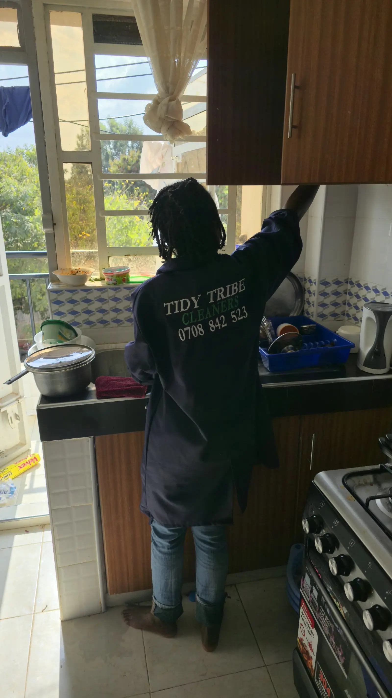 Cleaner in Tidy Tribe overalls wiping down kitchen surfaces during a deep clean