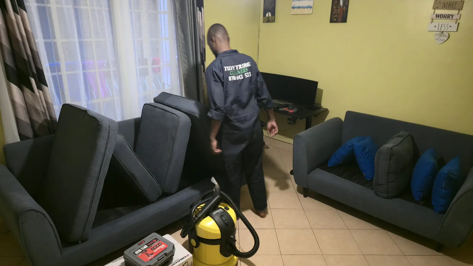 Sofa cushions lifted and lined up before cleaning, extractor machine ready
