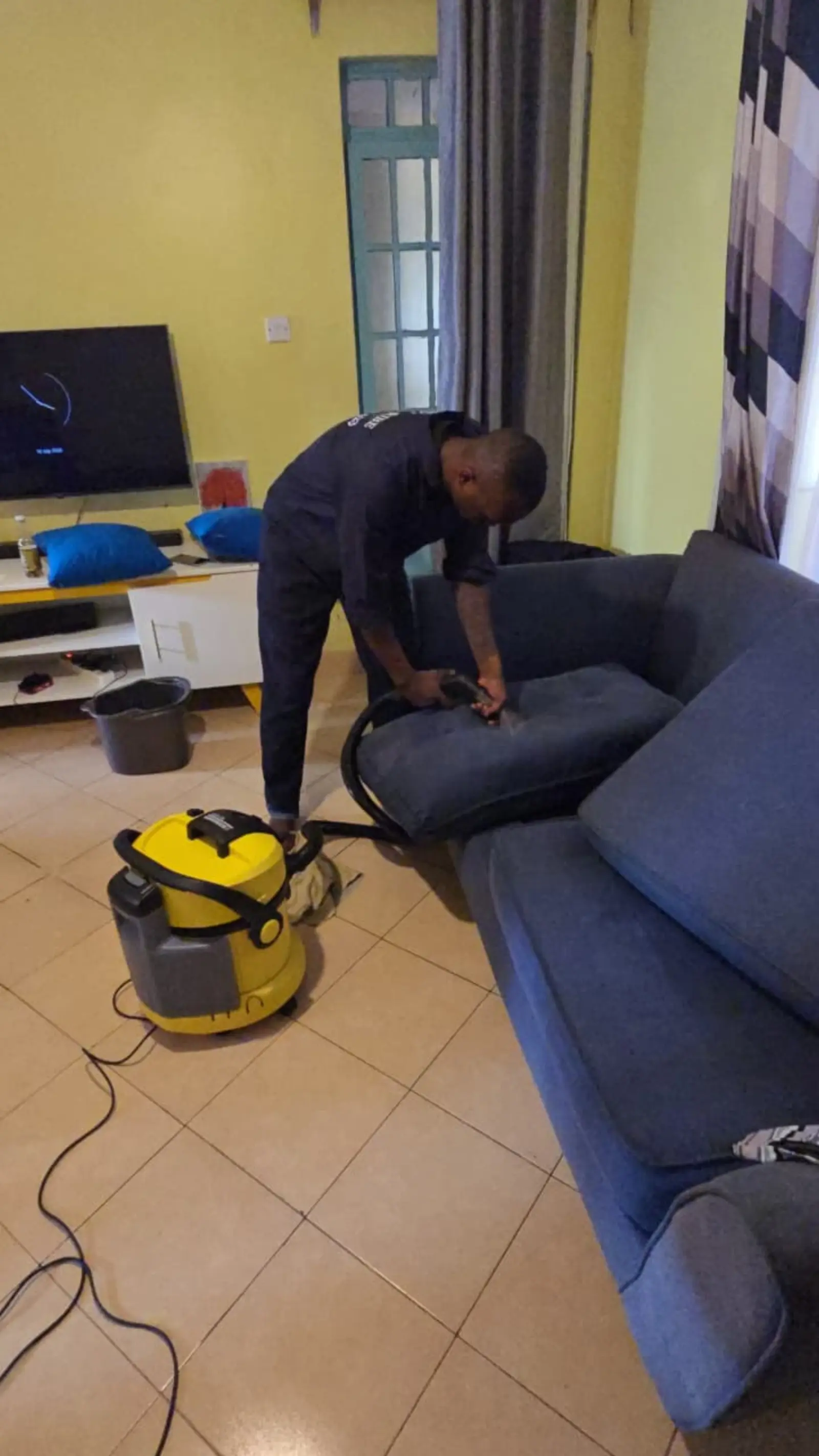 Cleaner working the extractor across a sofa back rest